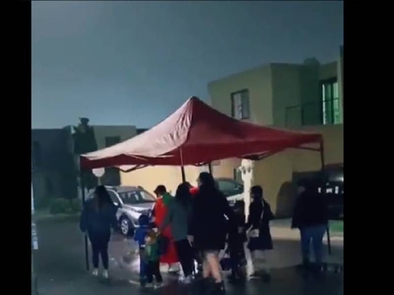 ¡Imparables! Con una carpa se cubren de la lluvia para pedir calaverita